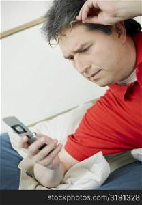 Close-up of a mature man looking at a mobile phone and reclining on the bed