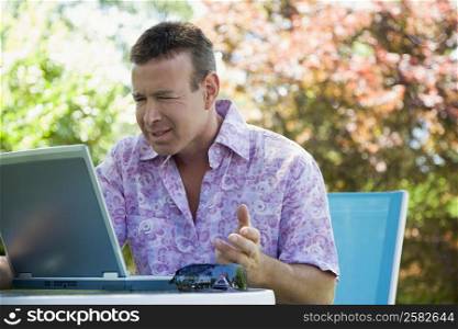 Close-up of a mature man looking worried while using a laptop