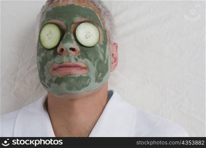 Close-up of a mature man lying on a massage table with facial mask on his face