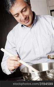 Close-up of a mature man preparing food in the kitchen and smiling