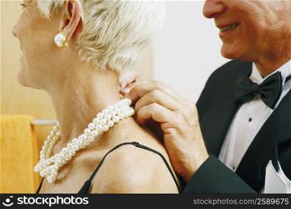 Close-up of a mature man putting a pearl necklace around a mature woman&acute;s neck