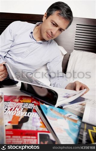 Close-up of a mature man reading a magazine on the bed