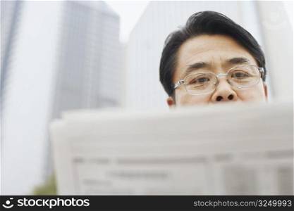 Close-up of a mature man reading a newspaper