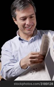 Close-up of a mature man reading a newspaper and smiling