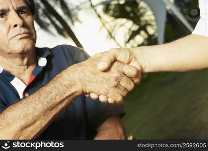 Close-up of a mature man shaking hands with another person