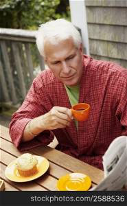 Close-up of a mature man sitting at the table and holding a cup of black tea