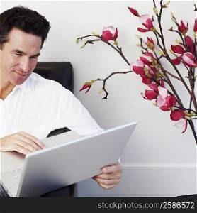 Close-up of a mature man sitting on a couch and using a laptop
