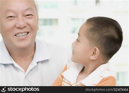 Close-up of a mature man smiling with his grandson looking at him