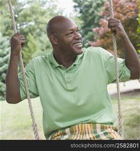 Close-up of a mature man swinging on a rope swing