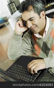 Close-up of a mature man talking on a mobile phone and using a laptop