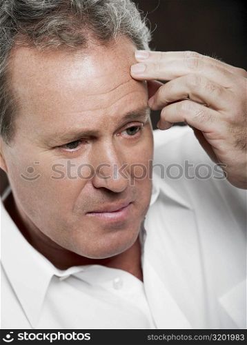 Close-up of a mature man touching his forehead