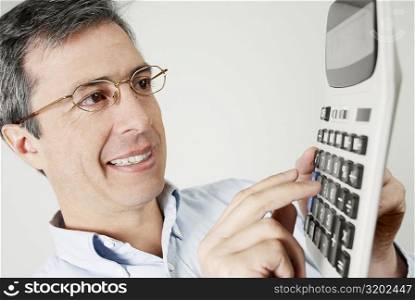 Close-up of a mature man using a calculator and smiling