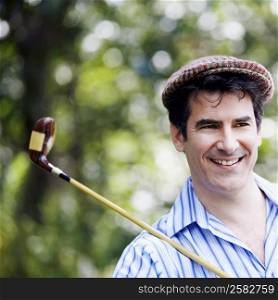 Close-up of a mature man with a golf club and smiling