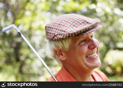 Close-up of a mature man with a golf club and smiling