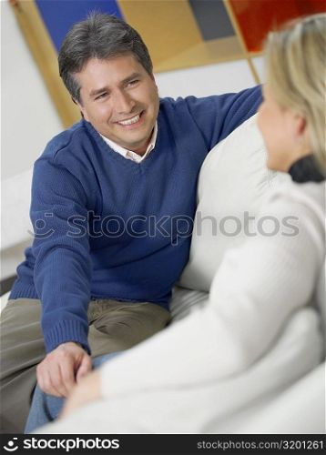 Close-up of a mature man with a mid adult woman sitting on a couch and looking at each other
