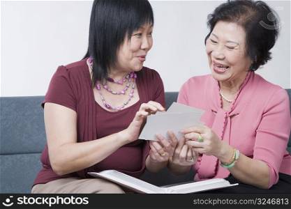 Close-up of a mature woman and a senior woman looking at photographs and smiling