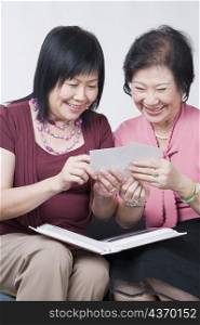 Close-up of a mature woman and a senior woman looking at photographs and smiling