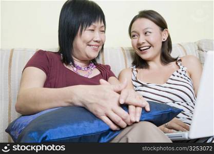 Close-up of a mature woman and her daughter using a laptop and smiling