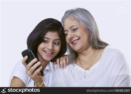 Close-up of a mature woman and her granddaughter looking at a mobile phone and smiling