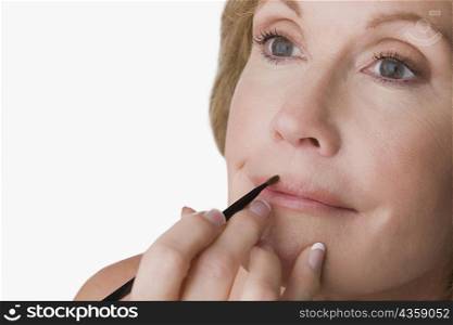 Close-up of a mature woman applying lip liner