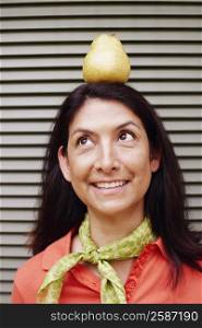 Close-up of a mature woman balancing a pear on her head
