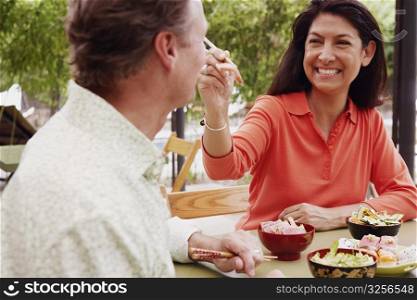 Close-up of a mature woman feeding a mature man with chopsticks
