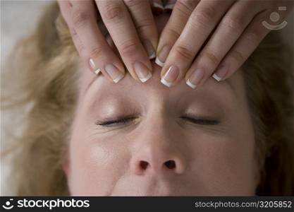 Close-up of a mature woman getting a forehead massage from a massage therapist