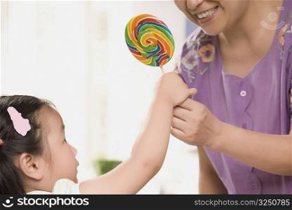 Close-up of a mature woman giving a candy to her granddaughter