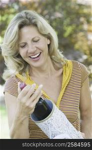 Close-up of a mature woman holding a champagne bottle and smiling