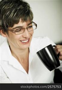 Close-up of a mature woman holding a cup of coffee and smiling