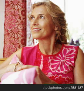 Close-up of a mature woman holding a cushion and looking away
