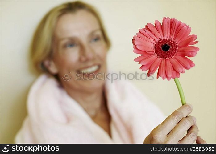 Close-up of a mature woman holding a gerbera daisy flower
