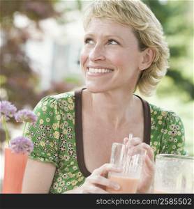 Close-up of a mature woman holding a glass of juice and smiling