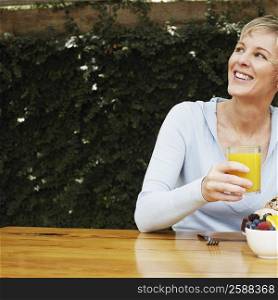 Close-up of a mature woman holding a glass of orange juice