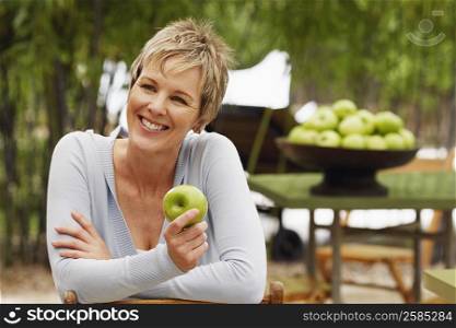 Close-up of a mature woman holding a granny smith apple and smiling