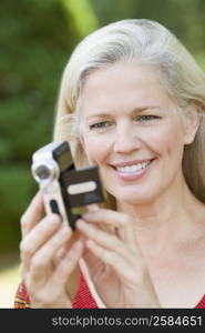 Close-up of a mature woman holding a home video camera and smiling