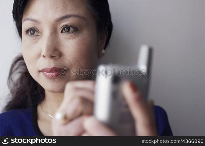 Close-up of a mature woman holding a mobile phone thinking