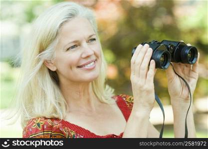 Close-up of a mature woman holding a pair of binoculars and smiling