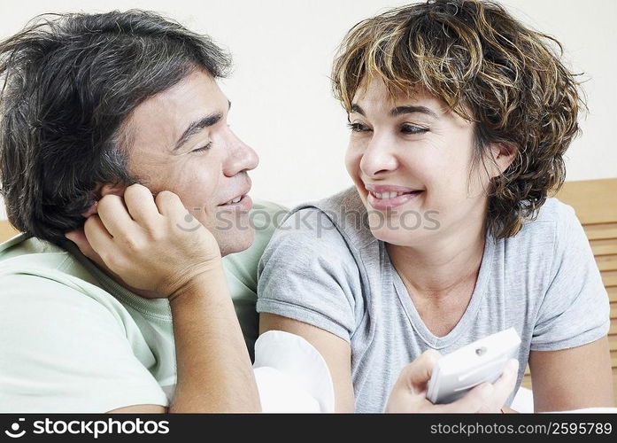 Close-up of a mature woman holding a remote control with a mature man looking at her