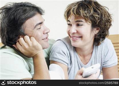 Close-up of a mature woman holding a remote control with a mature man looking at her