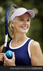 Close-up of a mature woman holding a tennis racket and a tennis ball