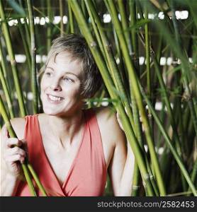 Close-up of a mature woman holding bamboo plants and smiling
