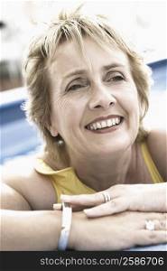 Close-up of a mature woman leaning on the ledge of a swimming pool and smiling