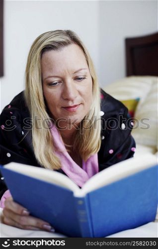 Close-up of a mature woman lying on the bed and reading a book