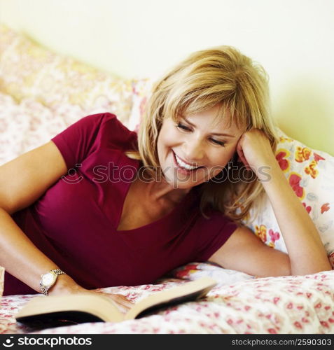 Close-up of a mature woman lying on the bed reading a book