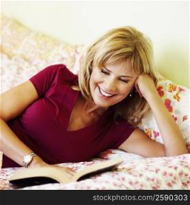 Close-up of a mature woman lying on the bed reading a book