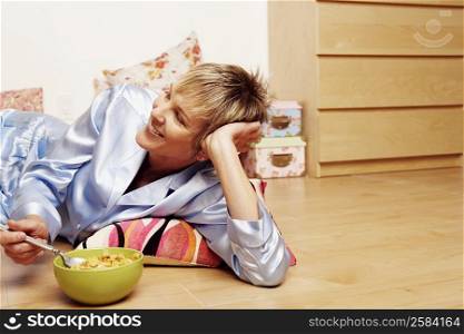 Close-up of a mature woman lying on the floor and eating corn flakes