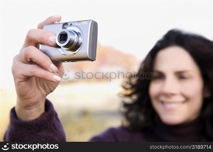 Close-up of a mature woman photographing with a digital camera