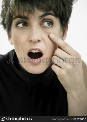 Close-up of a mature woman pointing towards her eye
