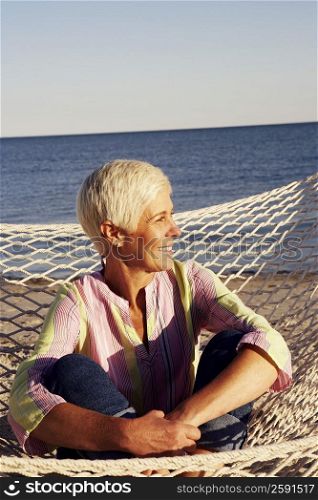 Close-up of a mature woman sitting in a hammock and smiling